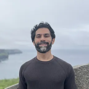 Portrait photo taken outdoors, with coastal cliffs in the background